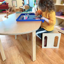 Load image into Gallery viewer, Child sitting at a table with a blue tray, engaged in an activity in a classroom setting.