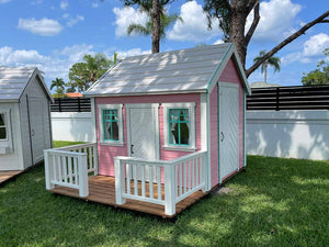 Pink Outdoor  Fully Finished Playhouse Unicorn with white roof, wooden terrace with white railing  on green lawn by WholeWoodPlayhouses