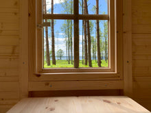 Load image into Gallery viewer, Wooden interior of wooden playhouse with a window view of trees and water by WholeWoodPlayhouses