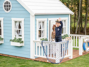 Boy waving on  Kids Outdoor Playhouse decorated wooden terrace with white railing by WholeWoodPlayhouses