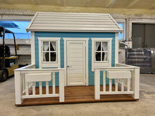 Load image into Gallery viewer, Small blue and white playhouse with a deck in WholeWoodPlayhouses woodshop