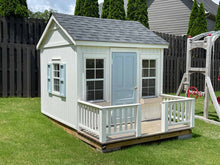 Load image into Gallery viewer, Playhouse Peachtree 8x8 view from left. The playhouse has white walls, a dark roof, and vertically opening shed windows with a screen. The playhouse has a blue solid wood door that opens onto a terrace with white wood railings. The side windows have blue shutters. There are natural wood flower boxes under the windows. By WholeWoodPlayhouses