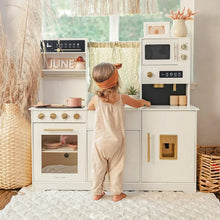 Load image into Gallery viewer, Child playing with a toy kitchen set in a bright room with large windows.
