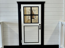 Load image into Gallery viewer, White wooden door with black frame and glass panel on a white wooden wall by WholeWoodPlayhouses