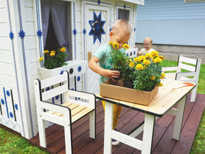Boy on the patio of the Kids Wooden Playhouse Cornflower by WholeWoodPlayhouses