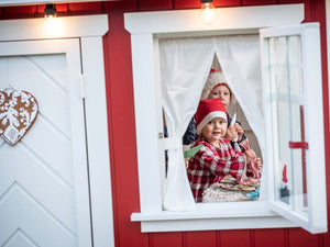 Kids decorating gingerbreads inside of the red Kids Playhouse Nordic Nario by WholeWoodPlayhouses