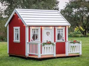 Red Outdoor Kids Playhouse Nordic Nario with white door and wooden terrace in a backyard by WholeWoodPlayhouses