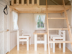 Inside View Of Kids OutDoor Playhouse Plum. Kids Furniture, One Bench, Two Chairs And A Table In kids Size. Solid Wood. Natural Wood Color Loft, Safety Railing And Ladder To Loft By WholeWoodPlayhouses