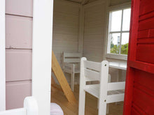 Load image into Gallery viewer, Inside view of Kids Playhouse Plum with kids furniture behind the red door by WholeWoodPlayhouses