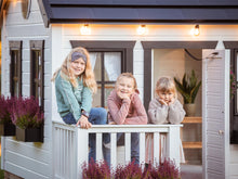 Load image into Gallery viewer, Kids are on the wooden terrace with white railing of Black and White Outdoor Playhouse by WholeWoodPlayhouses