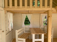Load image into Gallery viewer, Inside view with kids furniture, curtains and a loft with a round top window of a Wooden Playhouse Countryside by WholeWoodPlayhouses