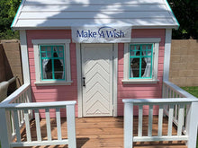 Load image into Gallery viewer, Closeup of front side of Pink Outdoor Playhouse Unicorn with  metal roof, two opening windows, white door, wooden terrace with white railing by WholeWoodPlayhouses
