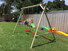 Load image into Gallery viewer, Side view of kids swing set Mathias with two swings by WholeWoodPlayhouses on a sunny day on green grass