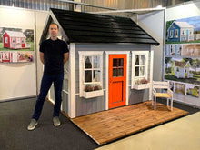 Load image into Gallery viewer, Man Who Made Wooden Playhouse Boy Cave With Wooden Terrace And Black Roof Stands Ahead of His Playhouse by WholeWoodPlayhouses
