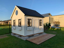 Load image into Gallery viewer, Outdoor Playhouse in black and white color with wooden terrace and a round top window in the backyard by WholeWoodPlayhouses
