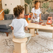 Load image into Gallery viewer, Two children playing with toys on a coffee table in a living room.
