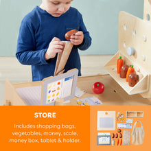 Load image into Gallery viewer, Child playing with a wooden toy set including vegetables, money, and a tablet holder.
