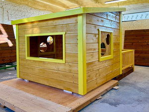 Wooden playhouse with yellow trim on a pallet indoors