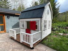 Load image into Gallery viewer, Kids Playhouse Farmhouse with  red dutch door, 4 opening windows and black metal roof in the backyard by WholeWoodPlayhouses
