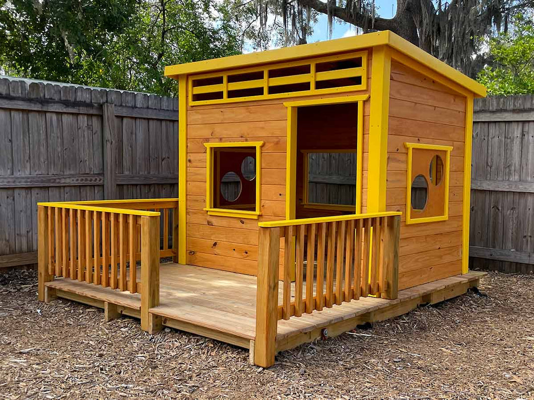 Front view of the Playhouse Chickadee 8x8 with vibrant yellow trim and natural wood finish, featuring a front porch and circular windows by WholeWoodPlayhouses