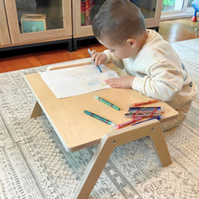Load image into Gallery viewer, Child drawing on a small wooden table with colorful pens in a home setting.

