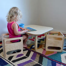 Load image into Gallery viewer, Child sitting at a small wooden table with two chairs on a colorful rug.
