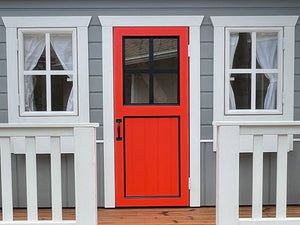 Red wooden door with black window panes on a gray playhouse by WholeWoodPlayhouses