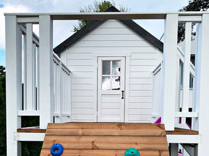 2-Story wooden playhouse Princess close up of the balcony and kids size white door with pink trims and window by WholeWoodPlayhouses