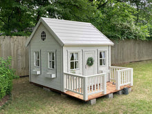 Load image into Gallery viewer, White Outdoor Kids Playhouse Snowy Owl With White Metal Roof, Brown Color Wooden Terrace and White Wooden Railing on Green Lawn Next To Gray Fence by WholeWoodPlayhouses 
