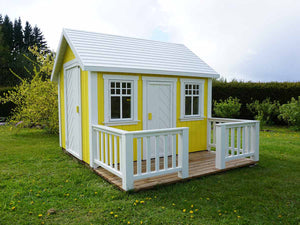 Yellow Wooden Playhouse Sunshine with white door and terrace on green lawn in a backyard by WholeWoodPlayhouses