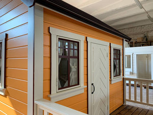 Close up of the windows  with white-brown trims and  white door of Kids Outdoor Playhouse Papaya by WholeWoodPlayhouses