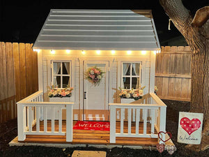 Closeup of  decorated Kids Playhouse Snowy Owl with flower boxes, wooden terrace and metal roof in the backyard by WholeWoodPlayhouses