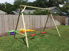 Load image into Gallery viewer, Mathias swing set with two swings for kids produced by WholeWoodPlayhouses on a sunny day on green grass in front of wooden fence
