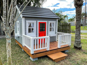 Kids Outdoor Wooden Playhouse Boy Cave With  Metal Roof, wooden terrace and Red Half Glass Door in the backyard By WholeWoodPlayhouses