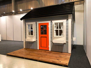 Front Outside View Of Gray Outdoor Kids Playhouse With Red Door And Wooden Terrace, Boy Cave by WholeWoodPlayhouses