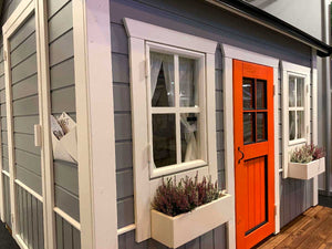 Close Up Of the Front White Windows, Gray Wall, White Flower Boxes And Red Door Of Outdoor Playhouse Kids Cave by WholeWoodPlayhouses