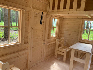 Inside of a wooden playhouse with loft and kids furniture by WholeWoodPlayhouses